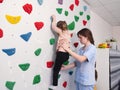 physiotherapist instructor helping little girl to climb wall in gym. sensory integration for kid and correctional Royalty Free Stock Photo