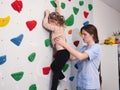 physiotherapist instructor helping little girl to climb wall in gym. sensory integration for kid and correctional Royalty Free Stock Photo