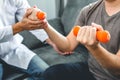 Physiotherapist man giving exercise with dumbbell treatment About Arm and Shoulder of athlete male patient Physical therapy Royalty Free Stock Photo