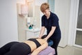 Physiotherapist massaging a female patient sportswoman with damaged muscles in kinesio clinic. Treatment of sports injuries