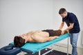 Physiotherapist massaging a male patient sportsman with damaged muscles in kinesio clinic. Treatment of sports injuries