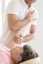 Physiotherapist stretching senior woman`s shoulder