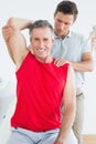 Physiotherapist stretching a smiling mature mans arm