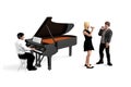 The pianist sits and plays the piano, with a boy and a girl standing next to him with microphones singing Royalty Free Stock Photo