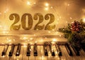 Piano keyboard with garlands of lights and Golden numbers 2022. Merry Christmas and New year concept Royalty Free Stock Photo