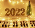 Piano keyboard with garlands of lights and Golden numbers 2022. Merry Christmas and New year concept. Selective focus Royalty Free Stock Photo