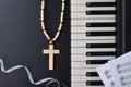 Piano with religious cross and silver bow on black table Royalty Free Stock Photo