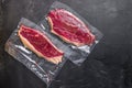 Picanha beef steak in vacuum sealed bag on black textured background, top view space for text