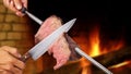 Picanha, Brazilian barbecue roasted over hot coals. Knife cutting a piece of meat on a skewer Royalty Free Stock Photo