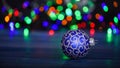 Pick colorful decor for christmas tree. Christmas ornament single ball on defocused garland colorful lights background