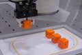 Pick and place robotic arm moving orange toy blocks at robot exhibition