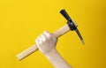 Pickaxe in man hand on yellow background. Advertising of tools for construction or dismantling.