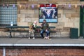 Couple sit with dog on a bench on an old railway platform