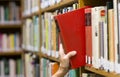 Woman Reaches out Picking a Book Library Shelf