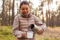 asian woman with thermos drinking tea in forest