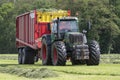 Picking up dried grass for silage with a tractor and loader wagon Royalty Free Stock Photo