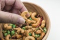 Picking up Thai spicy mixed nuts from wooden bowl Royalty Free Stock Photo