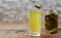 Pickle juice in glass and a can of pickled cucumbers on wooden table