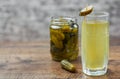 Pickle juice in glass and a can of pickled cucumbers on wooden table