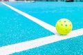 a pickleball ball on the line of a blue court, a new racket sport