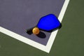 Pickleball and Blue Paddle on Edge of Court