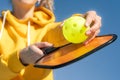 Pickleball paddle and yellow ball close up, woman playing pickleball game, hitting pickleball yellow ball with paddle