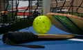 Pickleball paddles and yellow whiffle ball on blue court