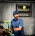 Pickleball player about to hit the yellow plastic ball with his paddle Royalty Free Stock Photo