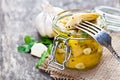 Pickled artichoke with garlic in a glass jar on rustic wooden t