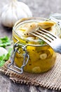 Pickled artichoke with garlic in a glass jar on rustic wooden t