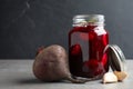 Pickled beets in glass jar on light table against background