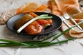 Pickled bell peppers of different colors, on a black matte plate, decorated with green onions, cutlery and a cloth napkin on