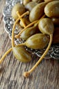 Pickled caper berries in metal dish .