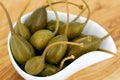 pickled caper berries in white bowl on wooden background, close up of capers Royalty Free Stock Photo