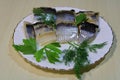 Pickled chopped herring with herbs on a white plate on the table.