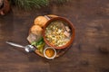 Pickled cucumber soup with pork and pearl barley and bread bun on wooden table Royalty Free Stock Photo