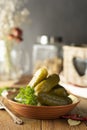 Pickled cucumbers in a bowl, rustic wooden background