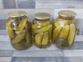 Pickled cucumbers in a glass jar. Three large jars of pickles on the table