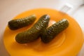 Pickled cucumbers in orange plate with fork on the table. Canned vegetables Royalty Free Stock Photo