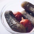 Pickled cucumbers and tomatoes in round glass dish