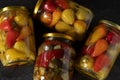 Pickled (fermented) vegetables in glass jars on dark background, top view