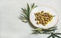 Pickled green Mediterranean olives in oil and olive tree branch Royalty Free Stock Photo