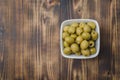 pickled green olives in a bowl on a wooden background. Top view, copyspace. Olives background