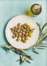 Pickled green olives, olive tree branch, virgin oil, blue background Royalty Free Stock Photo