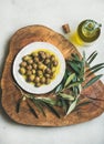 Pickled green olives and olive-tree branch on wooden board Royalty Free Stock Photo