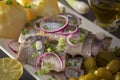 Pickled herring slices with red onion, fermented cucumber, potatoes, olives and lemon in a white plate Royalty Free Stock Photo