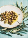 Pickled olives in oil and tree branch over blue background Royalty Free Stock Photo