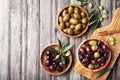 Pickled olives served in bowls from olive wood on rustic kitchen table top view.