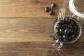 Pickled pitted black olives in glass jar, wooden background. Mediteranian foods. Copy space Royalty Free Stock Photo