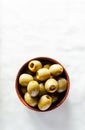 Pickled pitted green olives in a ceramic bowl on a light background. The concept of vegetarian food. Rustic style. Top view. Royalty Free Stock Photo